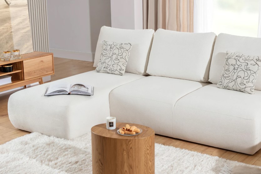 Biały narożnik z poduszkami i stolikiem w salonie